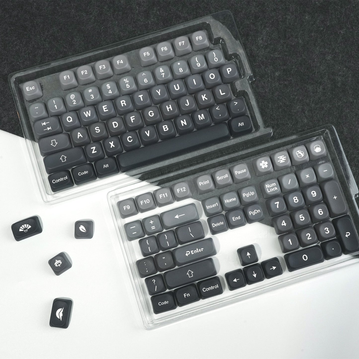PBT keycap sets in clear cases, dark and light gray key layouts