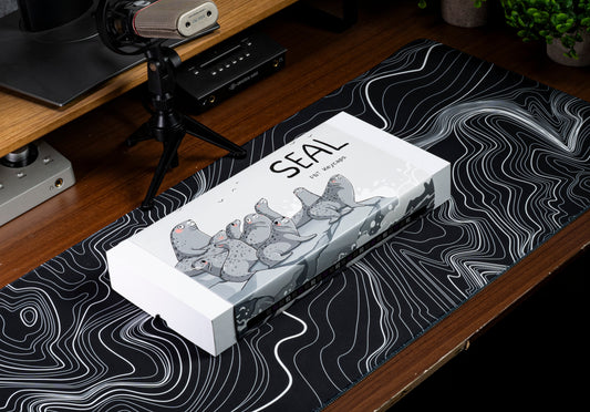 Keycap set box with seal-themed artwork and mixed dark and light keycaps inside