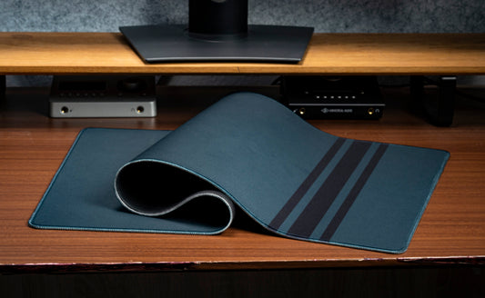 Blue desk mat with rolled edge and three stripe detail along one side