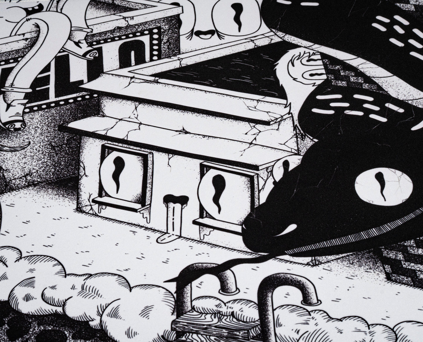 Black and white desk mat close-up showing small doors, clouds, and tentacle