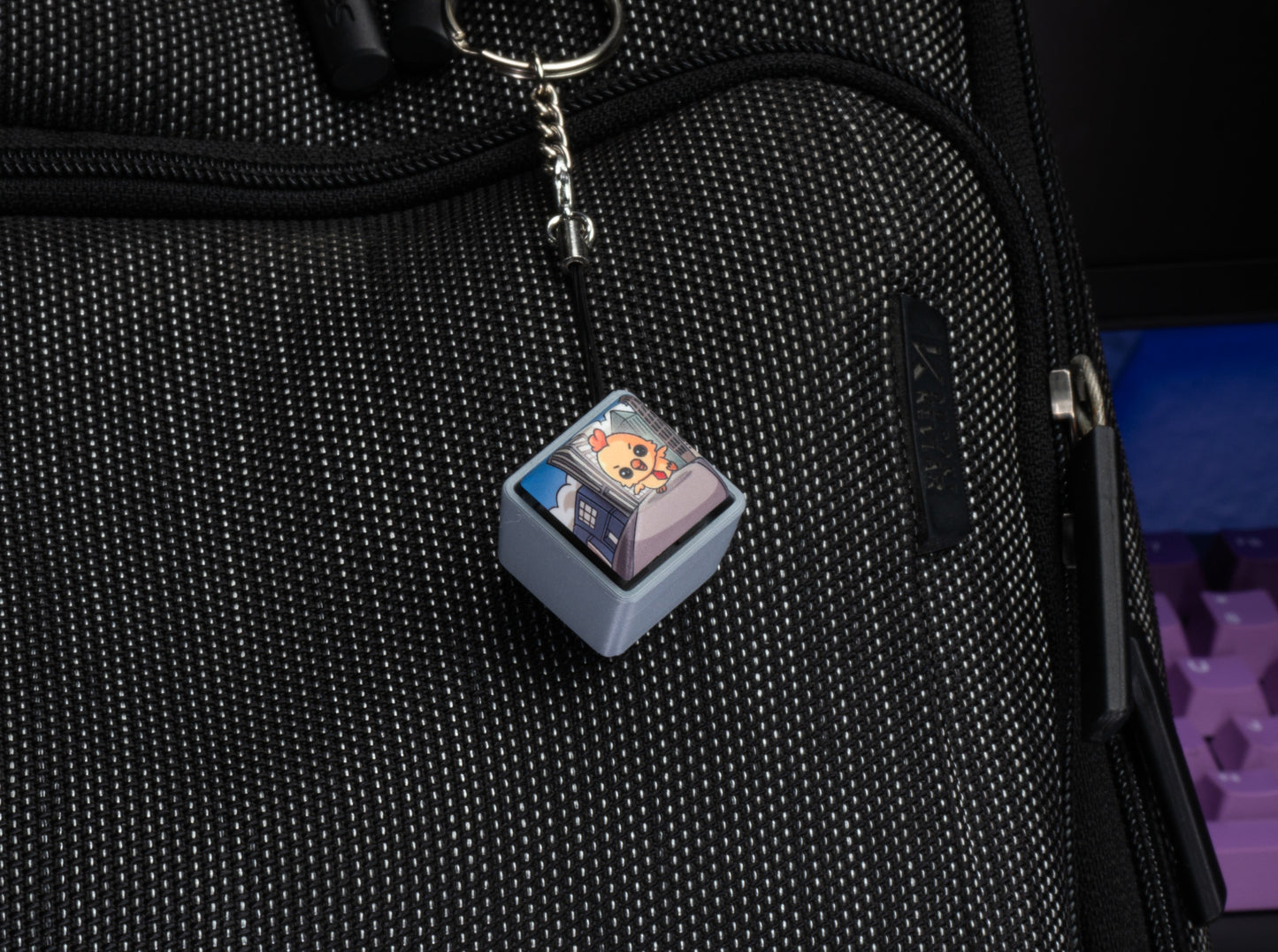Keycap charm fidget with silver chain on black zipper pull, light blue cartoon Hen keycap