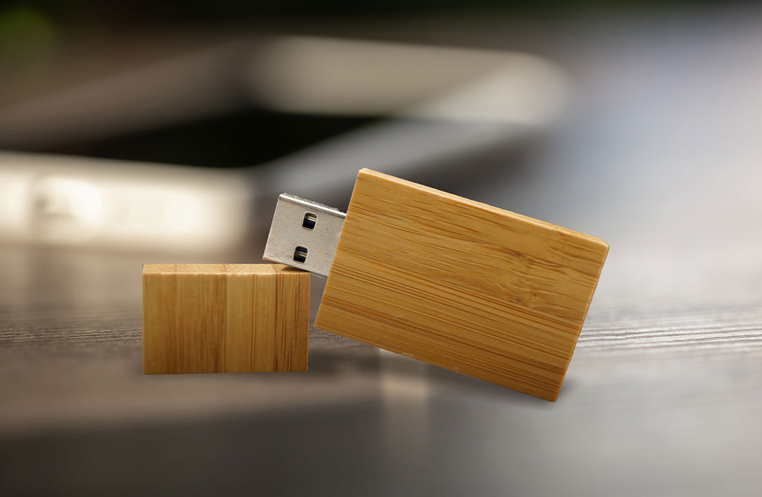 Wood USB flash drive plugged into laptop with silver USB connector, light bamboo tone