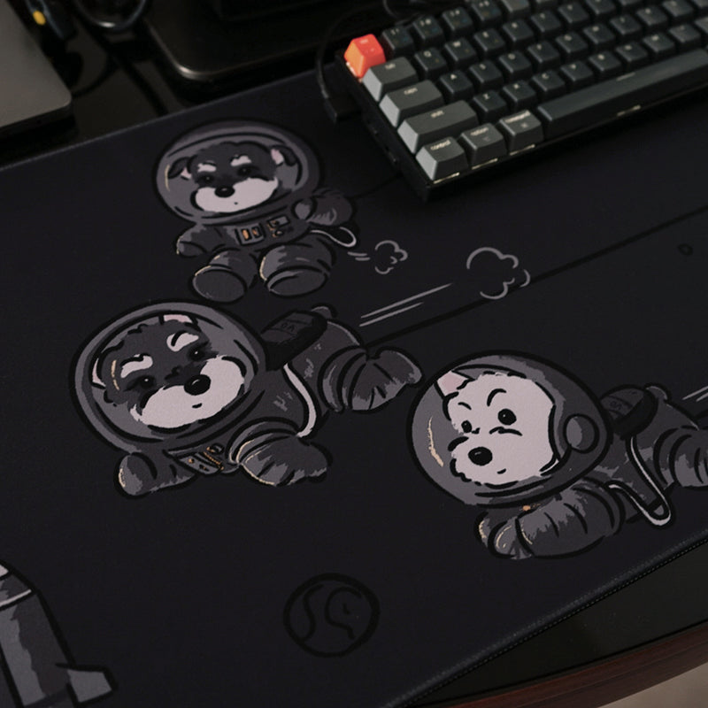 Black desk mat with cartoon space dogs, used under keyboard and mouse on desk