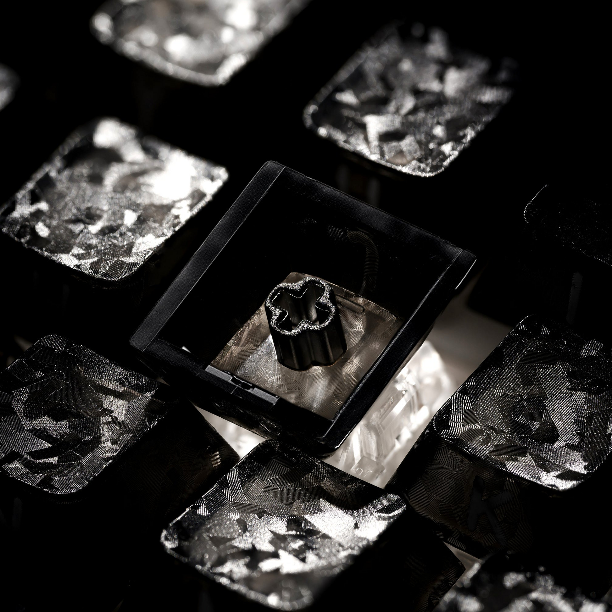 Mechanical keyboard keycap close-up with textured black and silver metallic surfaces