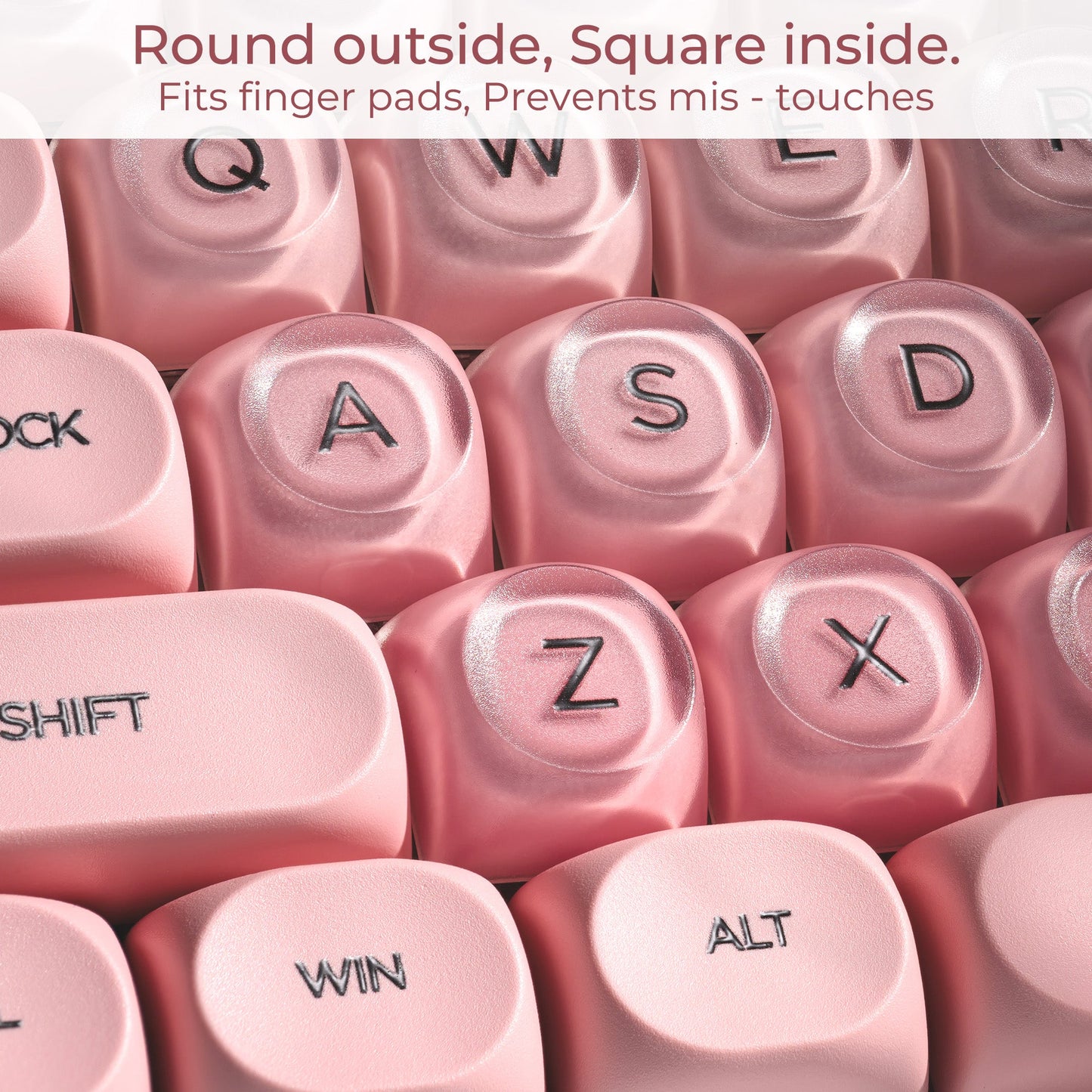 Close-up of blush pink keycaps with embossed letters and symbols, round top profile