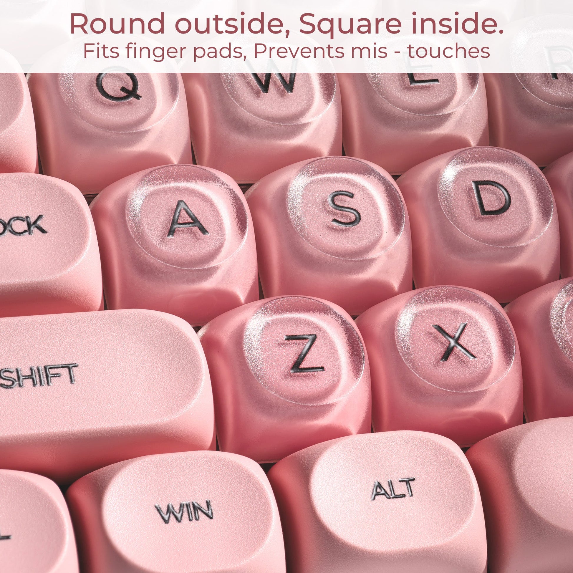 Close-up of blush pink keycaps with embossed letters and symbols, round top profile