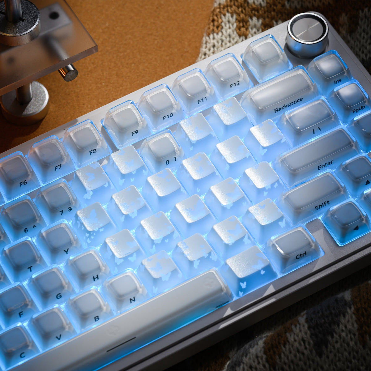 White keyboard keycaps with blue backlight; butterfly pattern accents and key legends