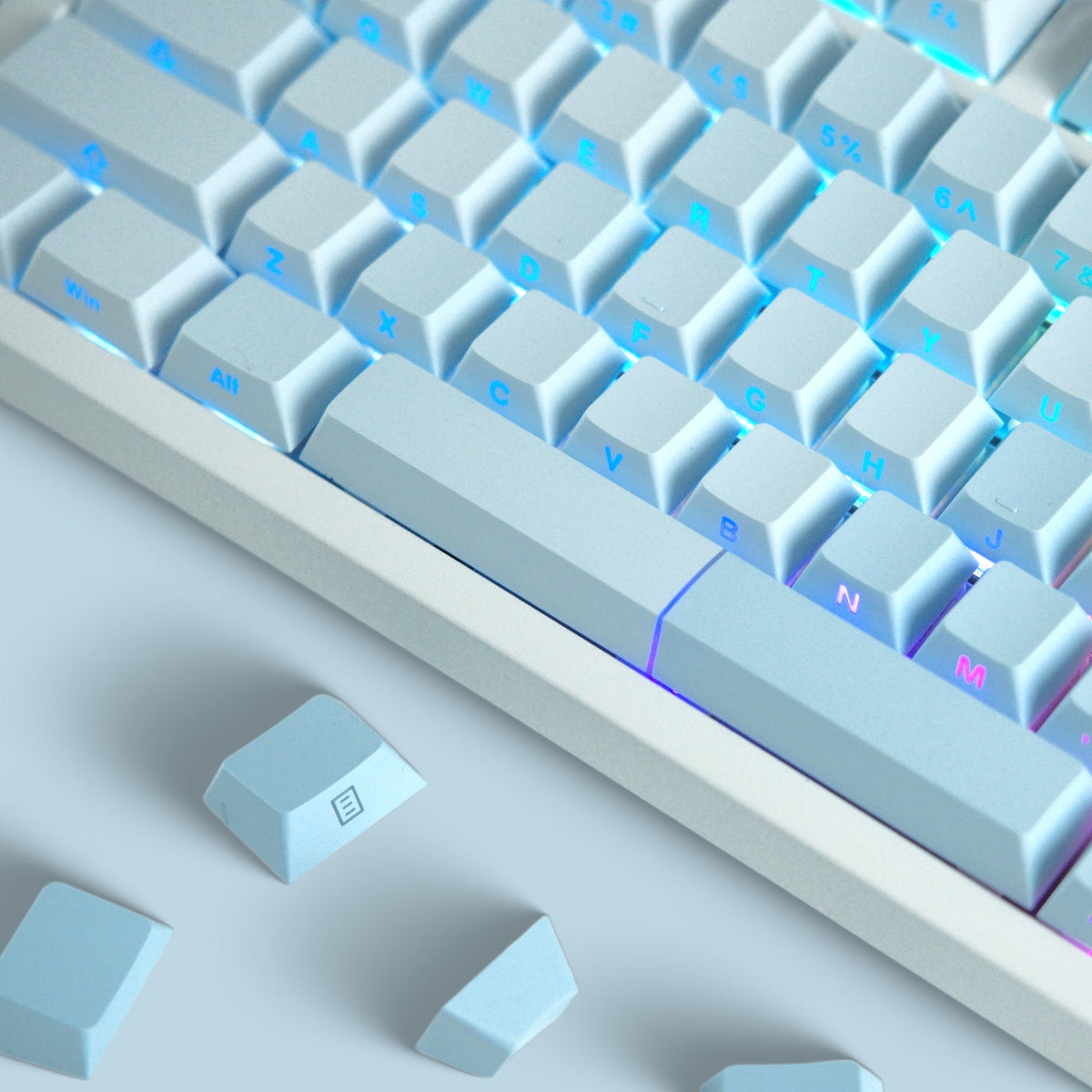 Cherry-profile keycap set close-up, light blue keys with bright blue illuminated legends