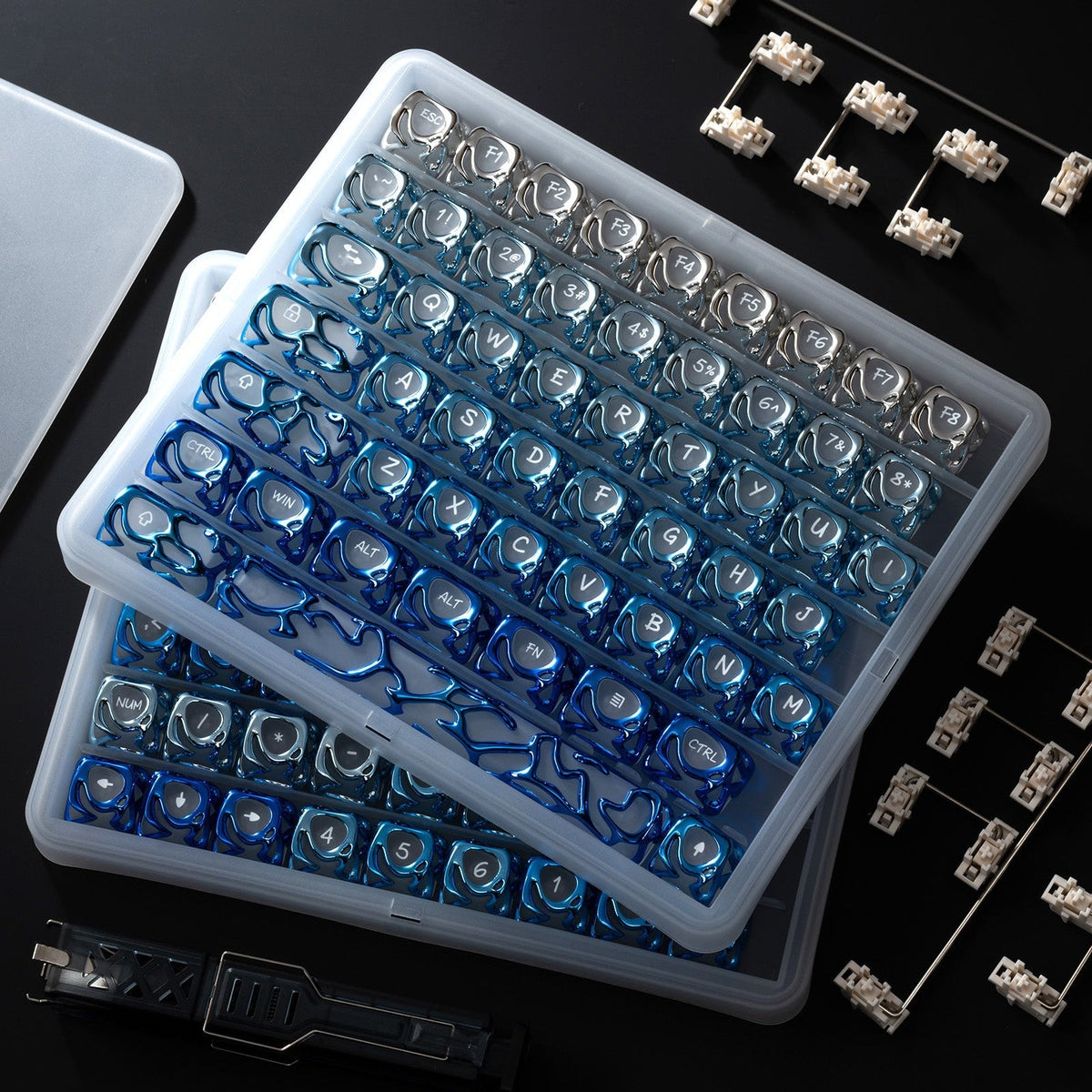 Blue venom-style liquid metallic keycap set in clear tray, with loose keycaps
