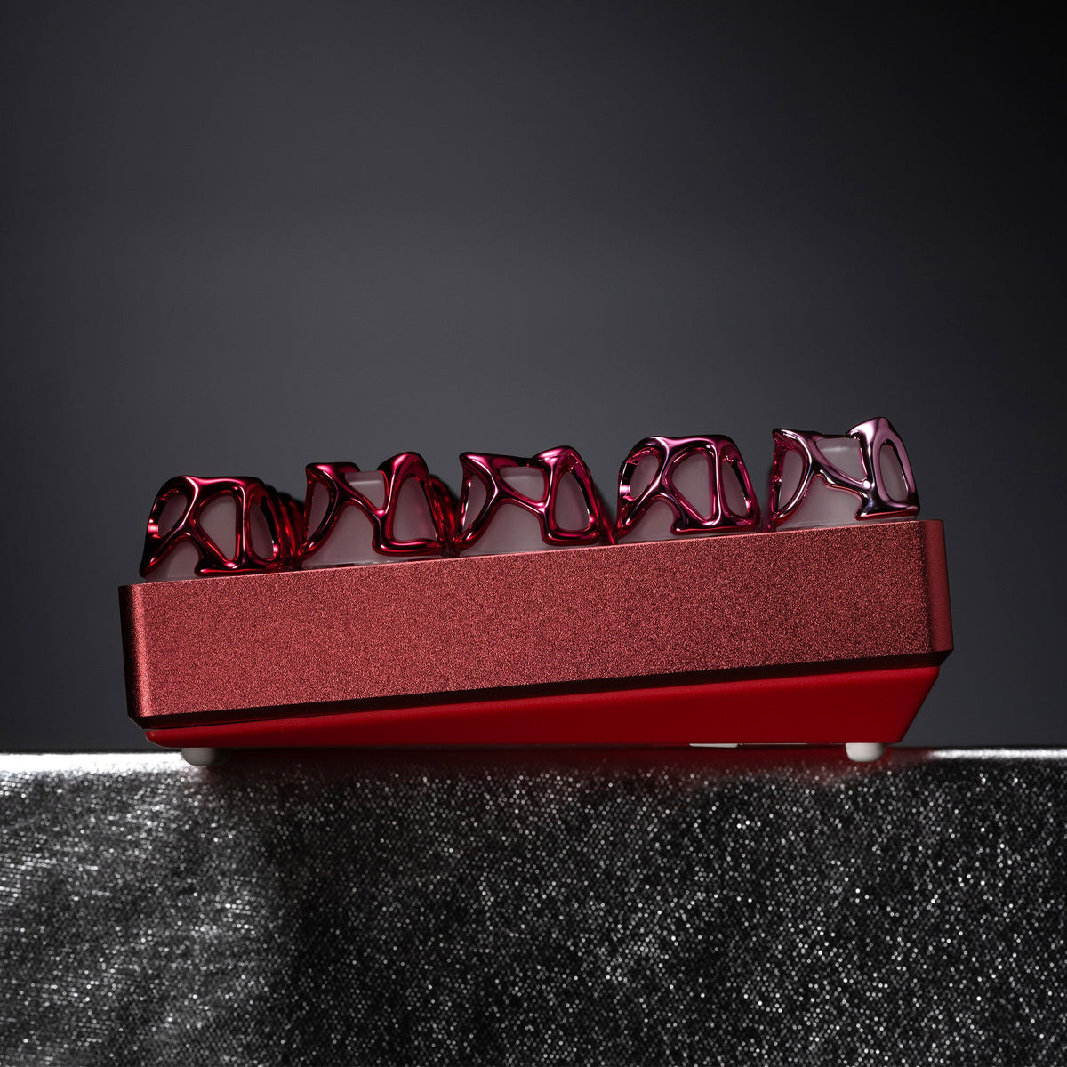 Venom-style liquid metallic keycaps, pink/red, full row view on tray