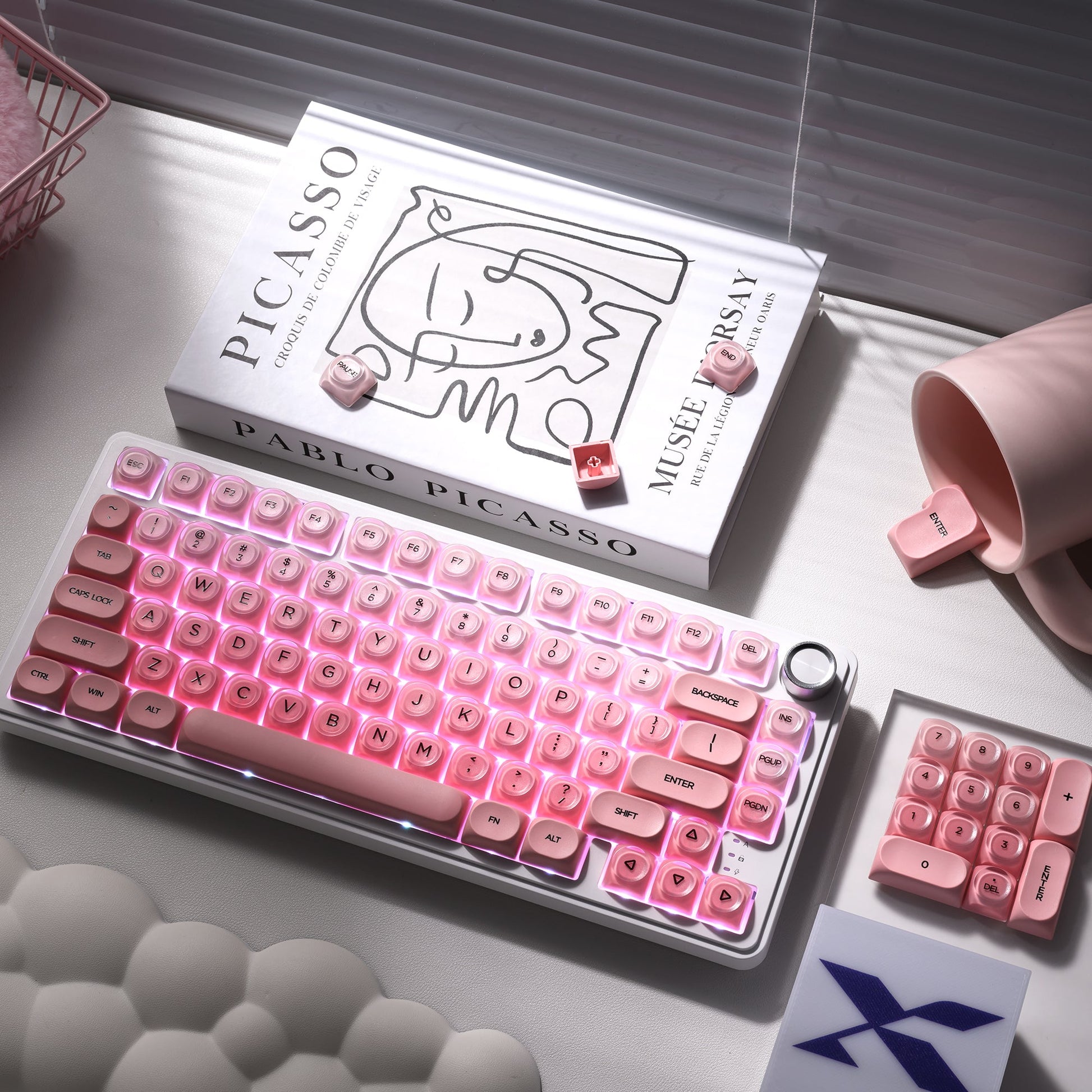 Blush pink mechanical keyboard keycaps in metal tray with a few extra keys nearby