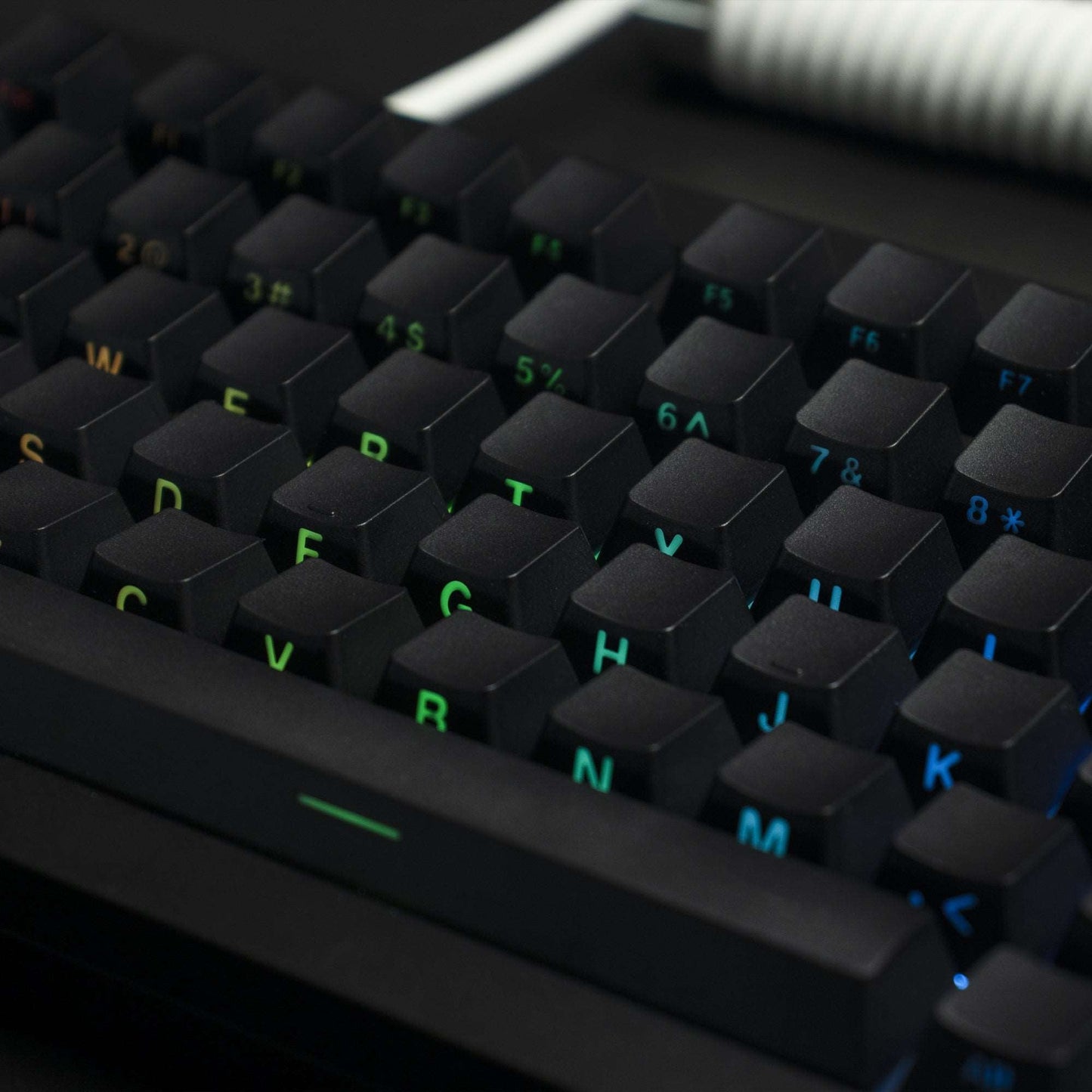 Close-up of dark OEM profile keycaps with side-printed letters and green-blue backlit legends