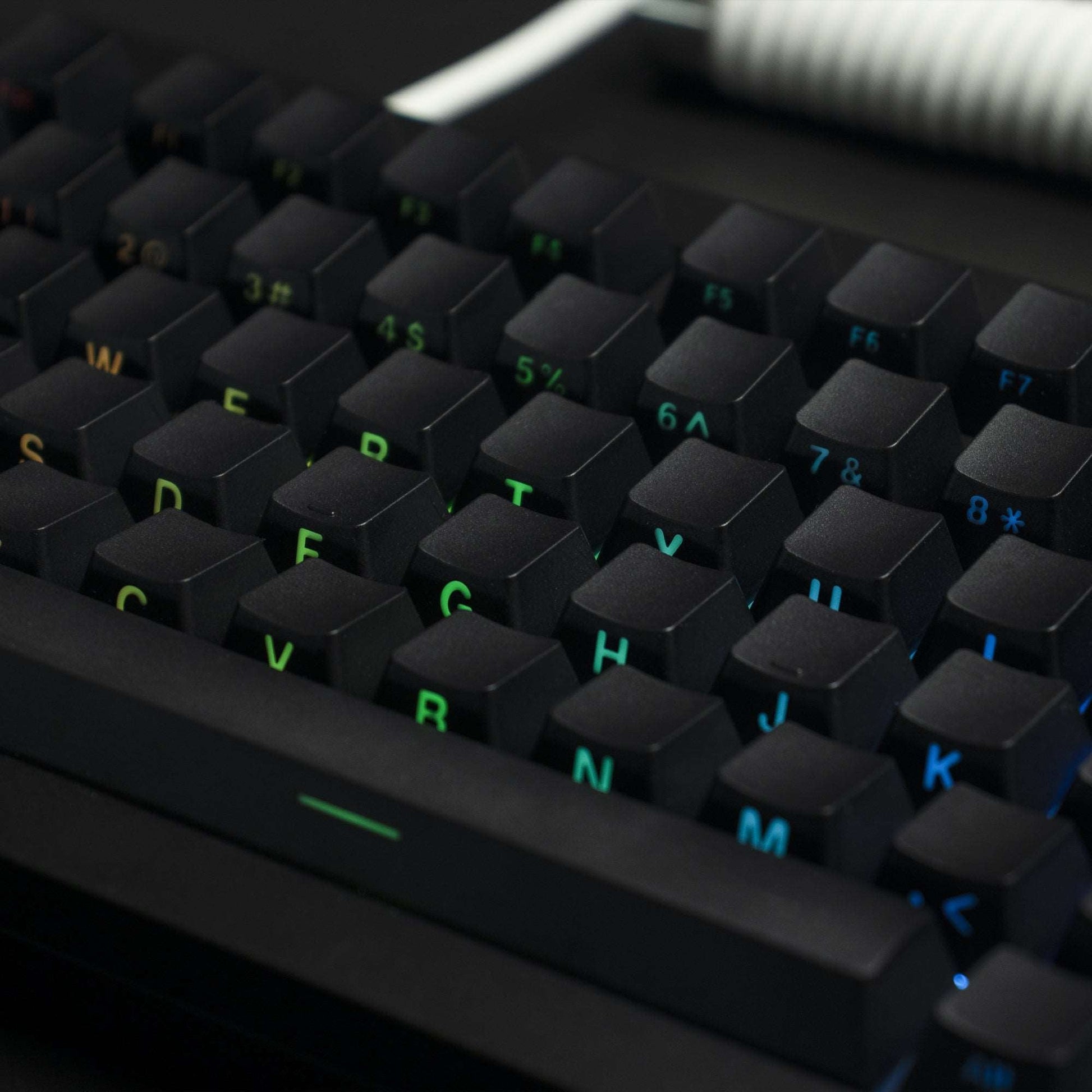 Close-up of dark OEM profile keycaps with side-printed letters and green-blue backlit legends
