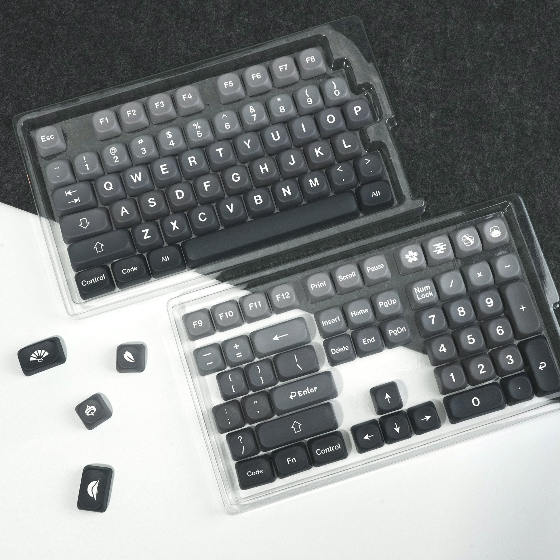 PBT keycap sets in clear cases, dark and light gray key layouts