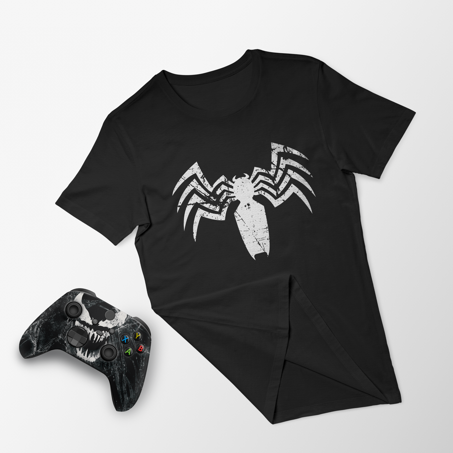 Black graphic T-shirt with white spider emblem; black Xbox controller, front view