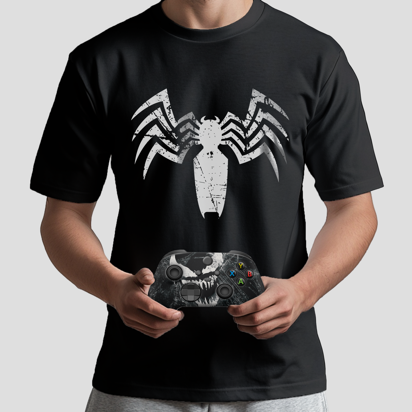 Black graphic T-shirt with white spider emblem; Xbox controller held in front