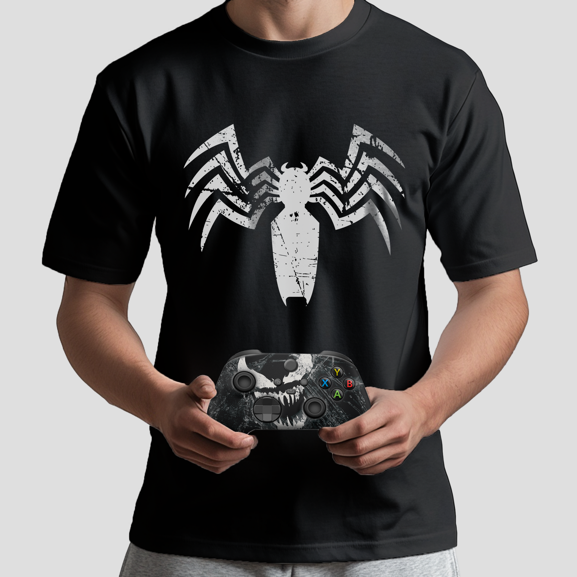 Black graphic T-shirt with white spider emblem; Xbox controller held in front