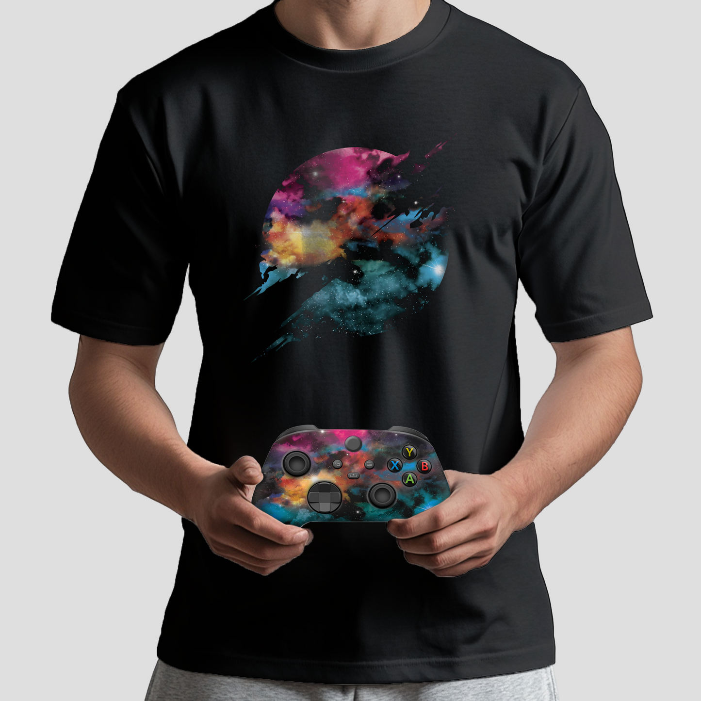 Person wearing black galaxy T-shirt while holding Xbox controller with nebula design