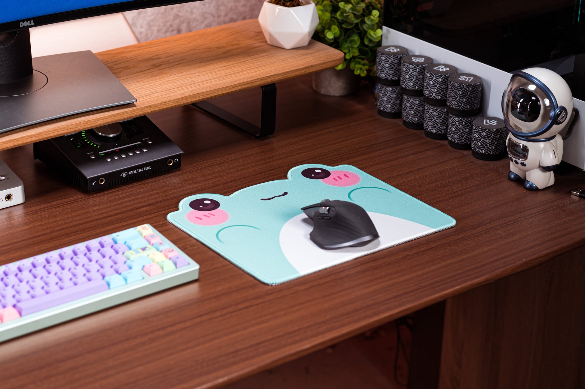 Turquoise frog desk mat with white belly graphic, pink cheek faces, and a small topper
