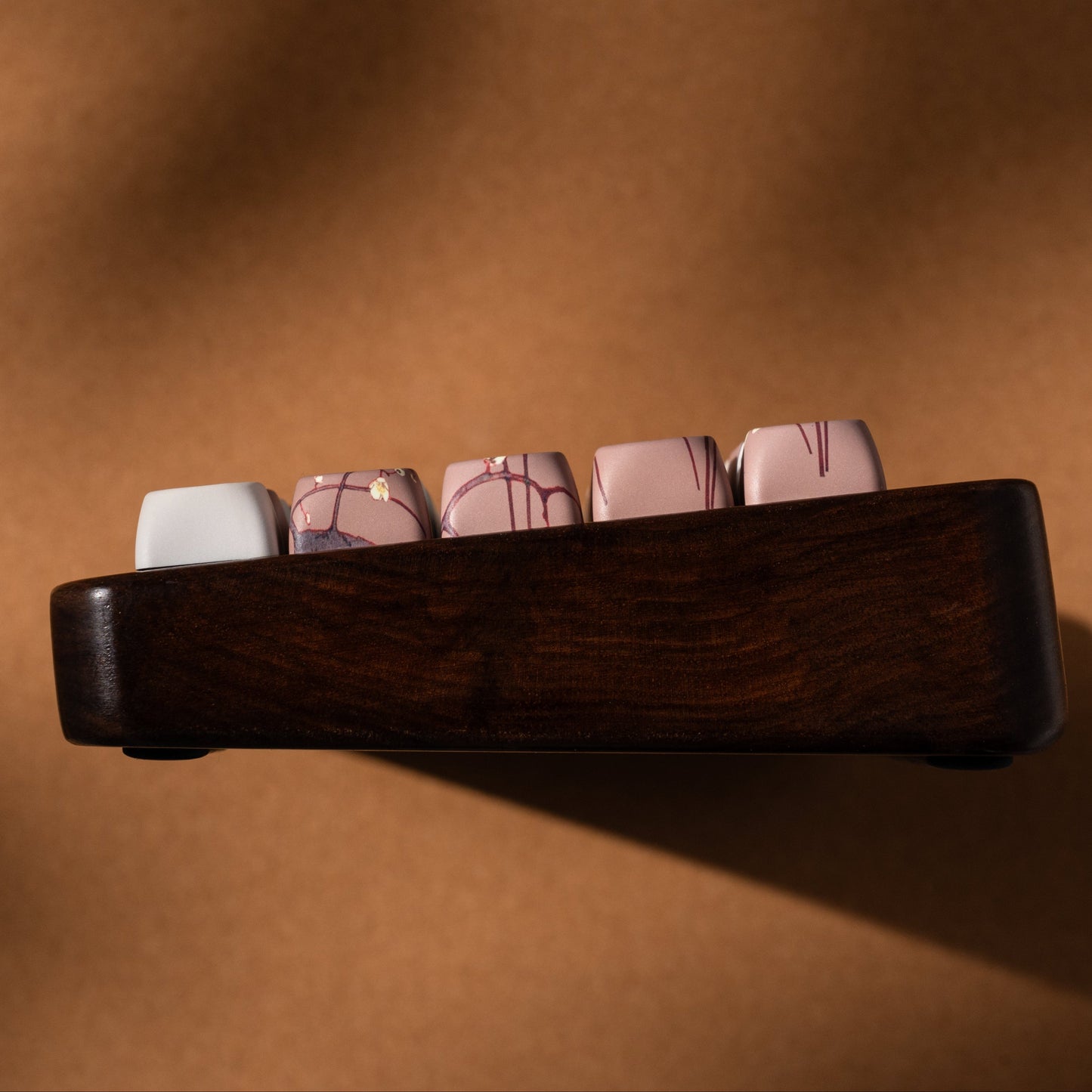 Keycap set row in wooden holder with cream and muted pink and gray keycaps