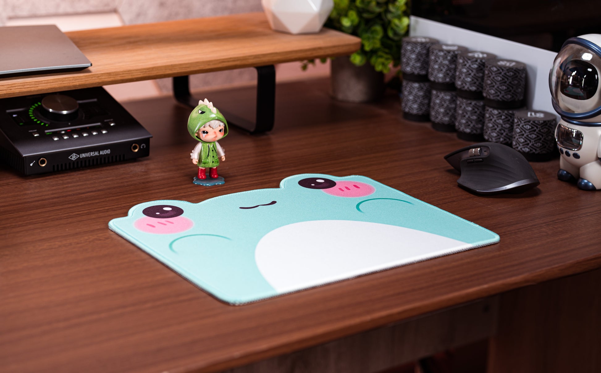Turquoise frog desk mat with white belly graphic and pink cheek faces, used on a desk