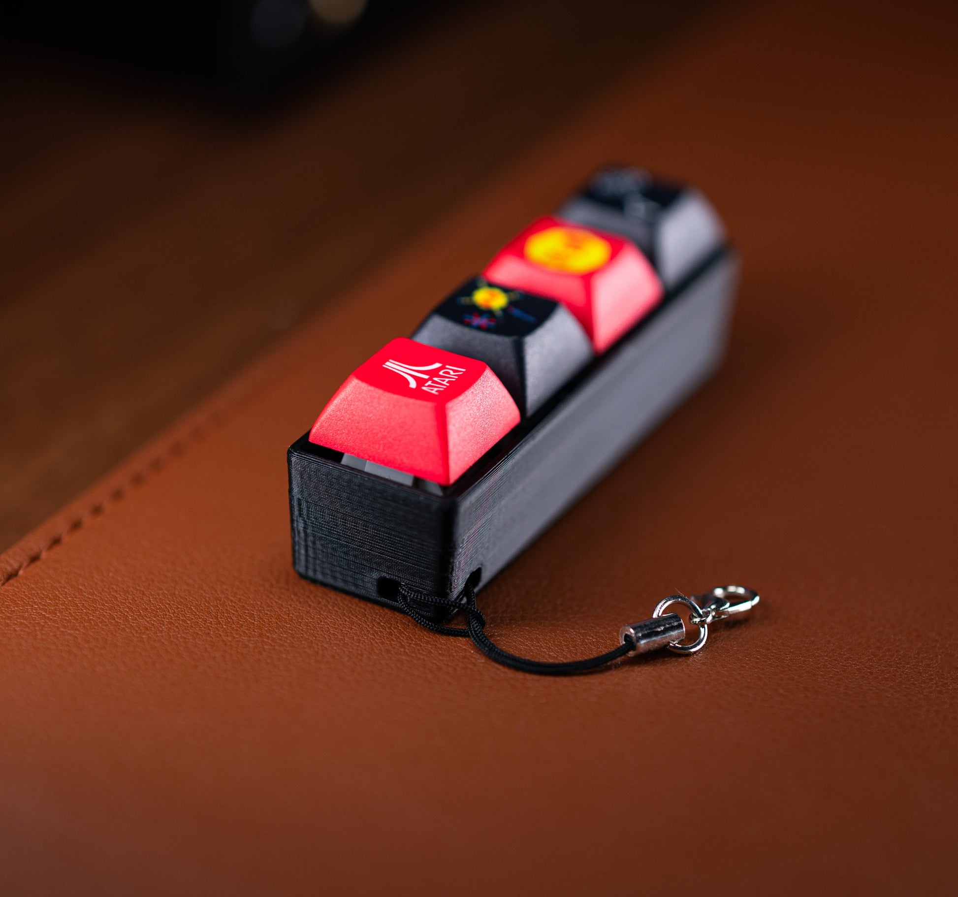 Atari Keycap Fidget with red keycaps on black base and attached keychain