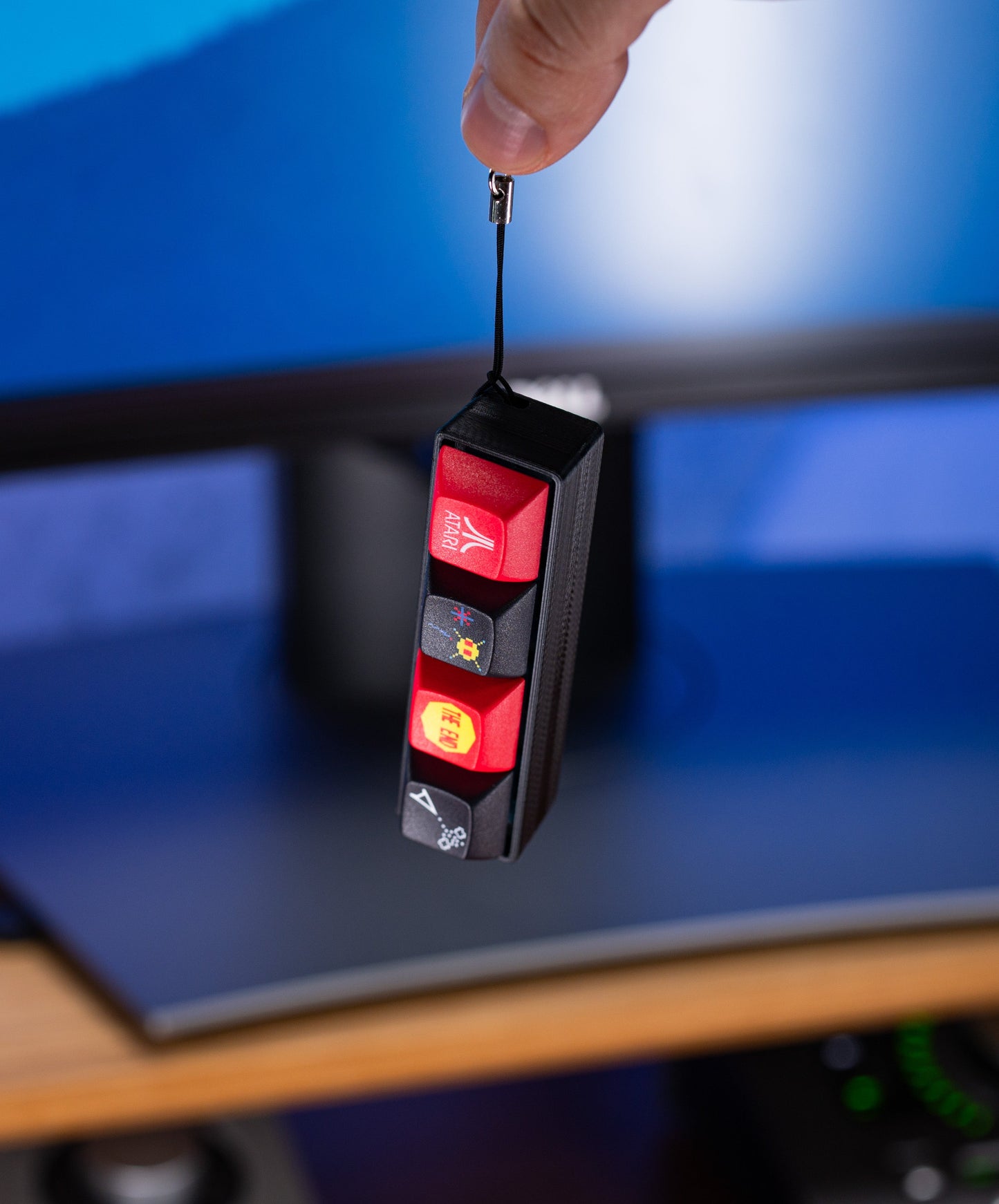 Atari Keycap Fidget held by hand; red keycaps on a black base with keychain