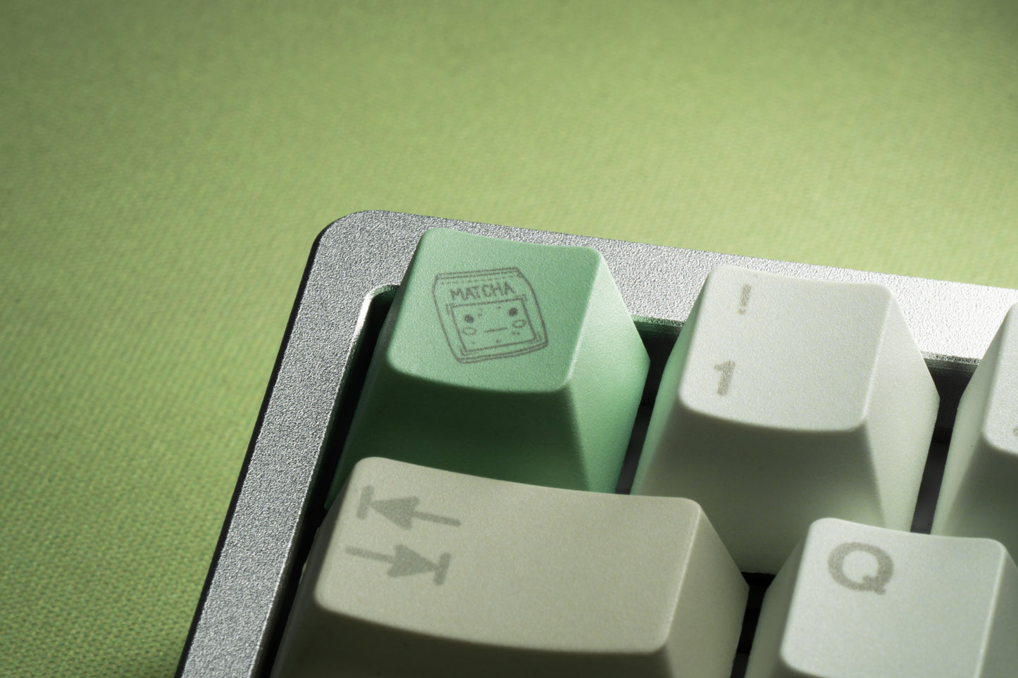 Macro view of white PBT keycaps with mint-green icons and a textured surrounding keycap