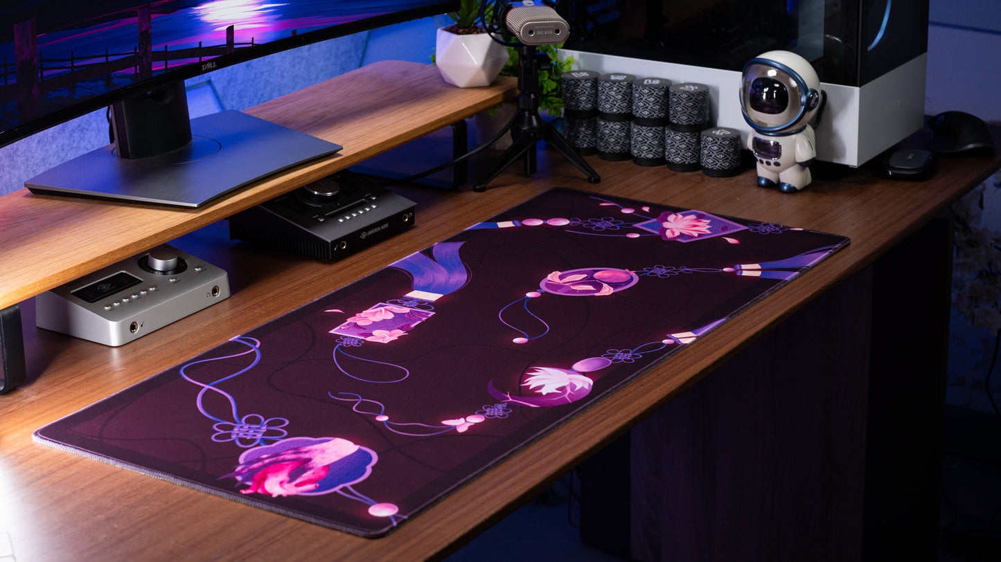 Rectangular desk mat with dark purple floral design and pink accents, flat on desk