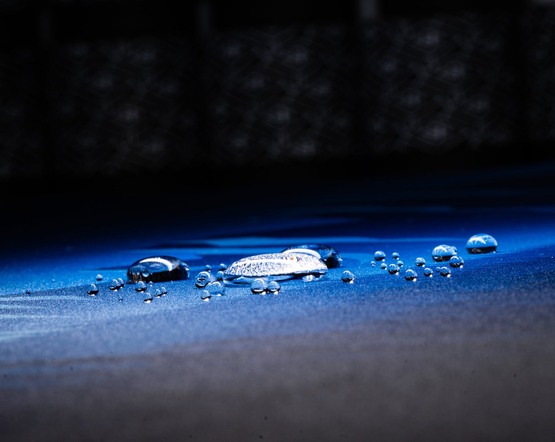 Blue desk mat surface with water droplets on starry mountain print