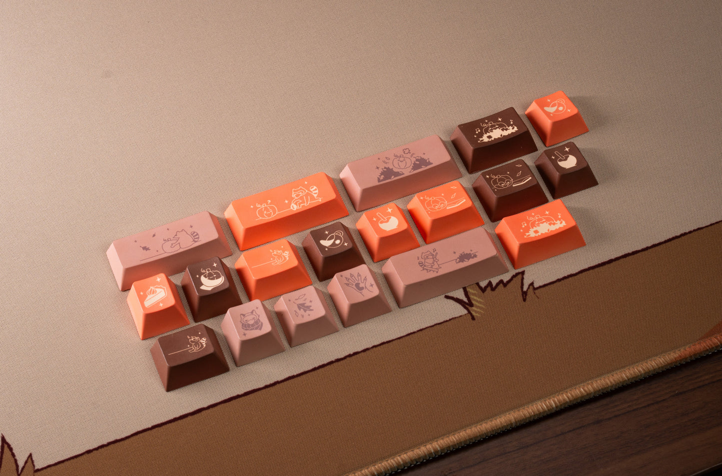 Assorted pumpkin-themed keycaps in beige, brown, and orange scattered on mat edge