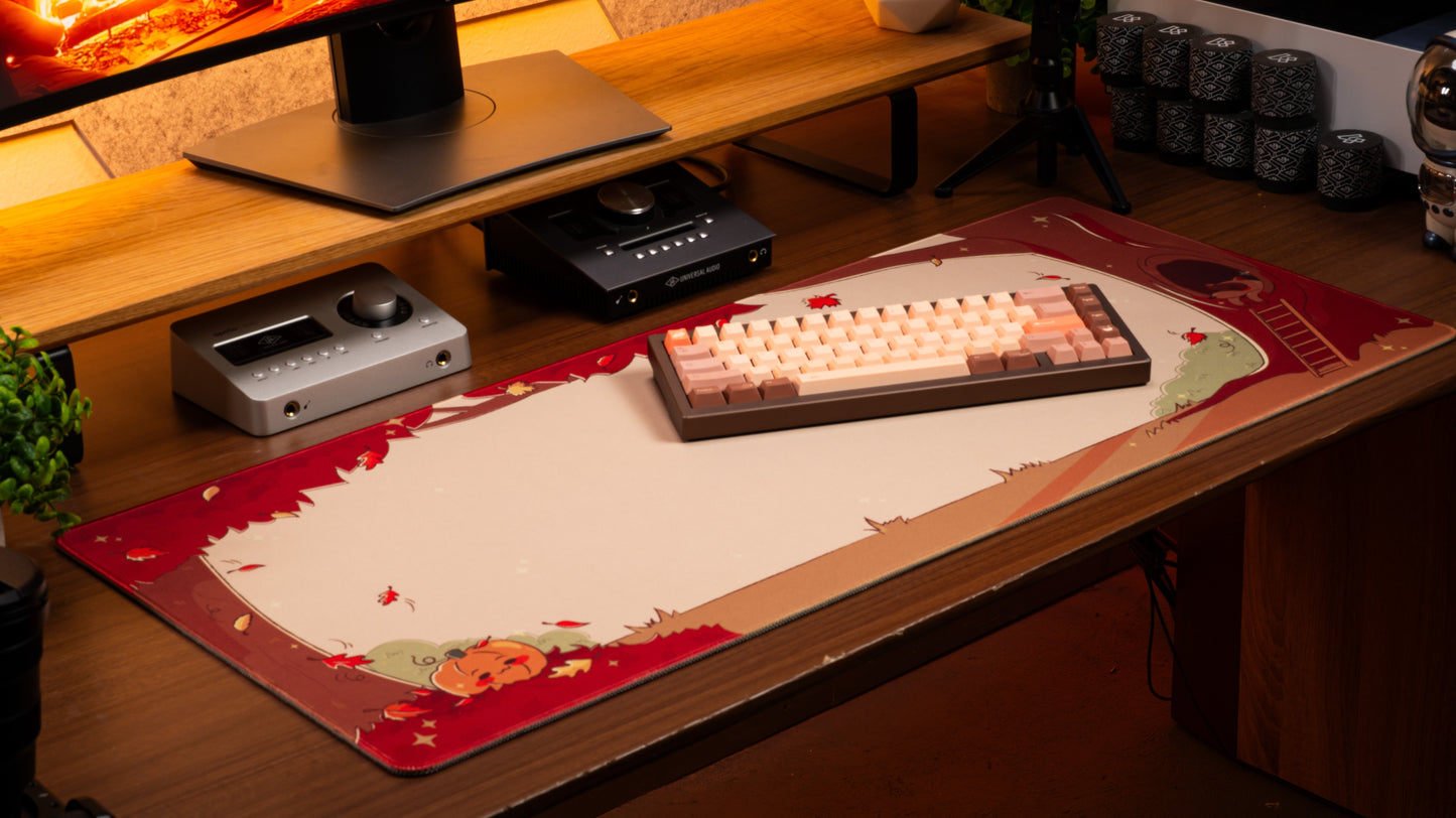 Pumpkin desk mat on wooden desk with keyboard and devices, red and cream seasonal design