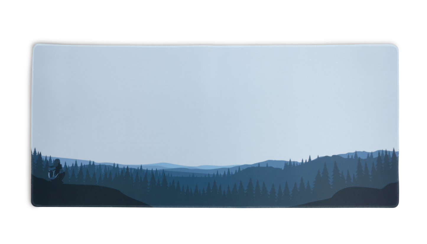 Rectangular desk mat with blue forest and hills graphic, stitched border