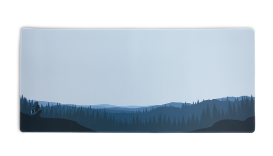 Rectangular desk mat with blue forest and hills graphic, stitched border