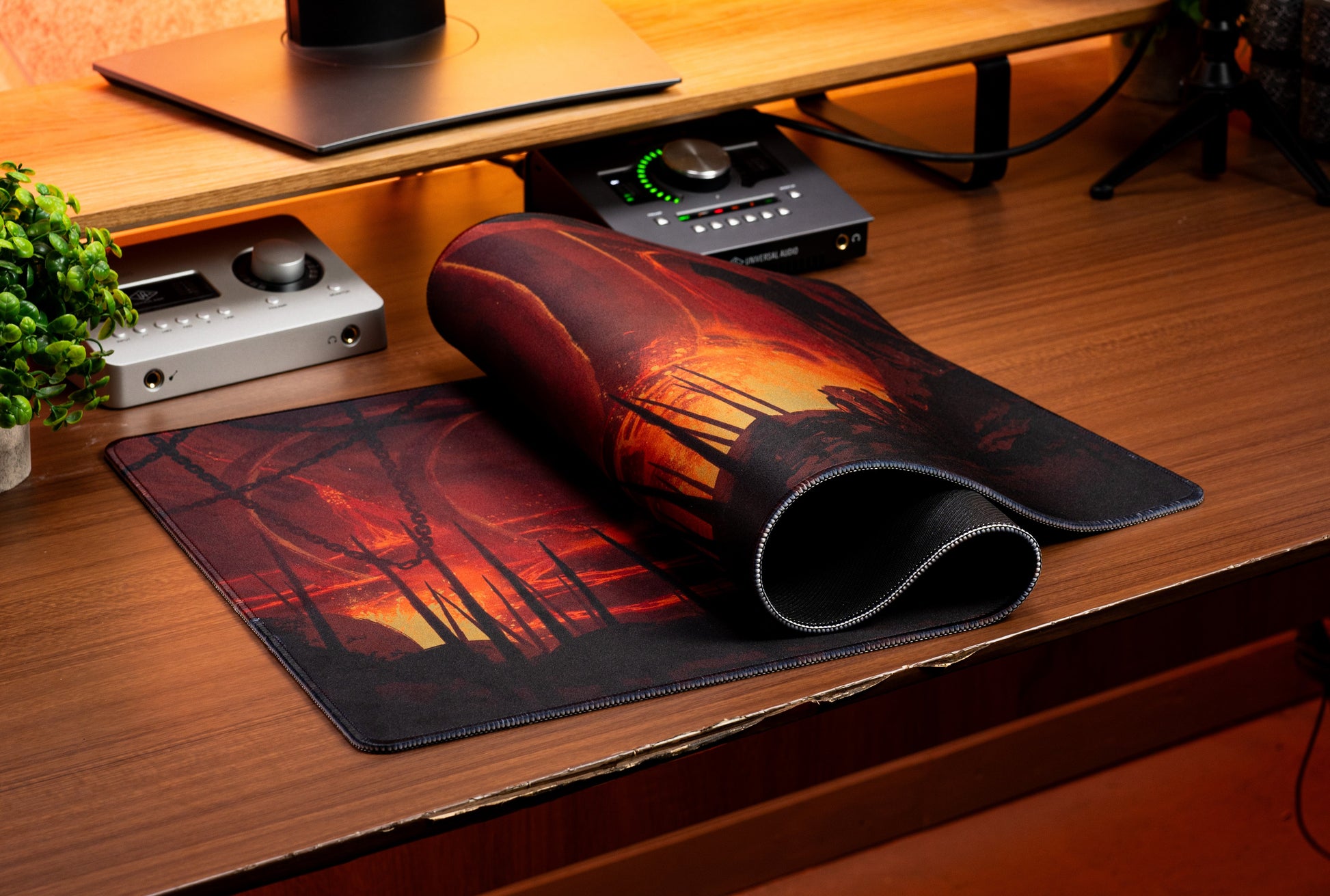 Desk mat with fiery landscape print, showing black underside along folded edge