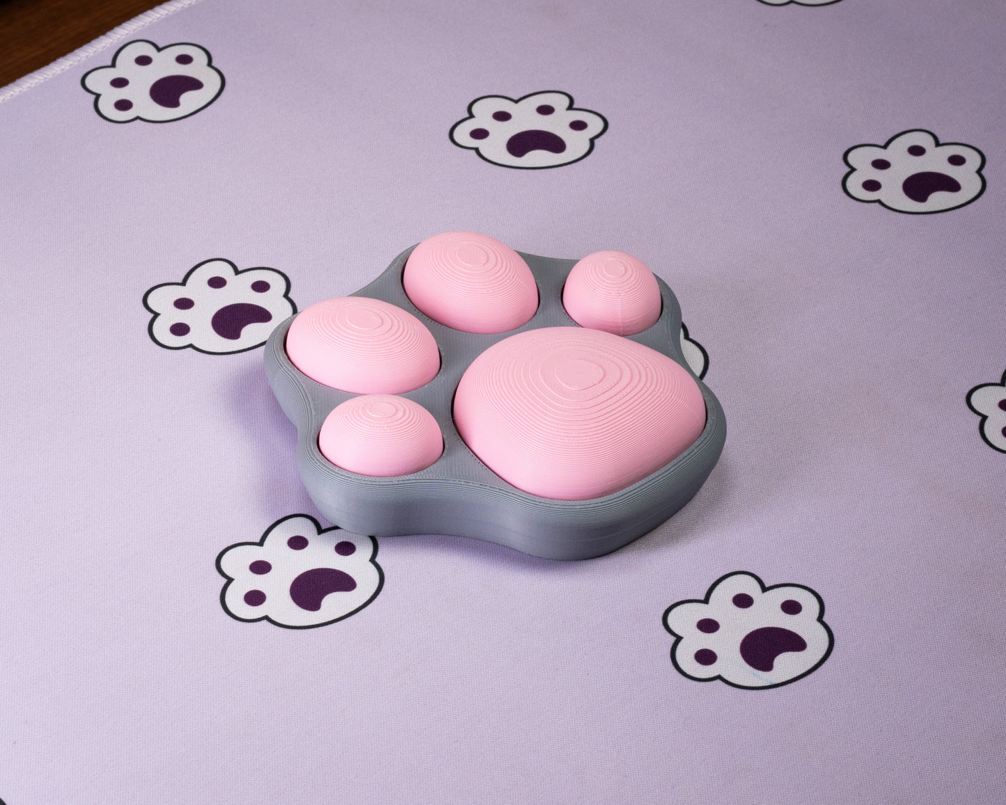 Cat-paw fidget with multiple pink ridged pads on a gray base
