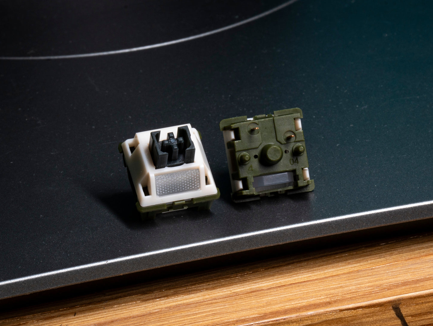 Tactile keyboard switch housings, one cream with metal contacts and one olive-green
