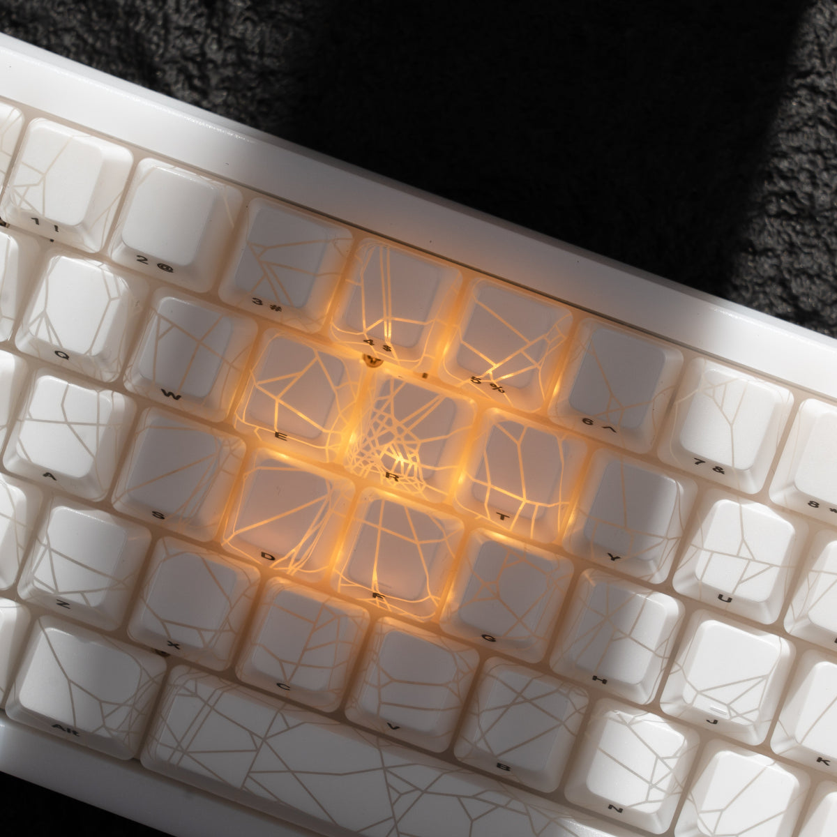 White mechanical keyboard top close-up with warm orange RGB spider-web lighting