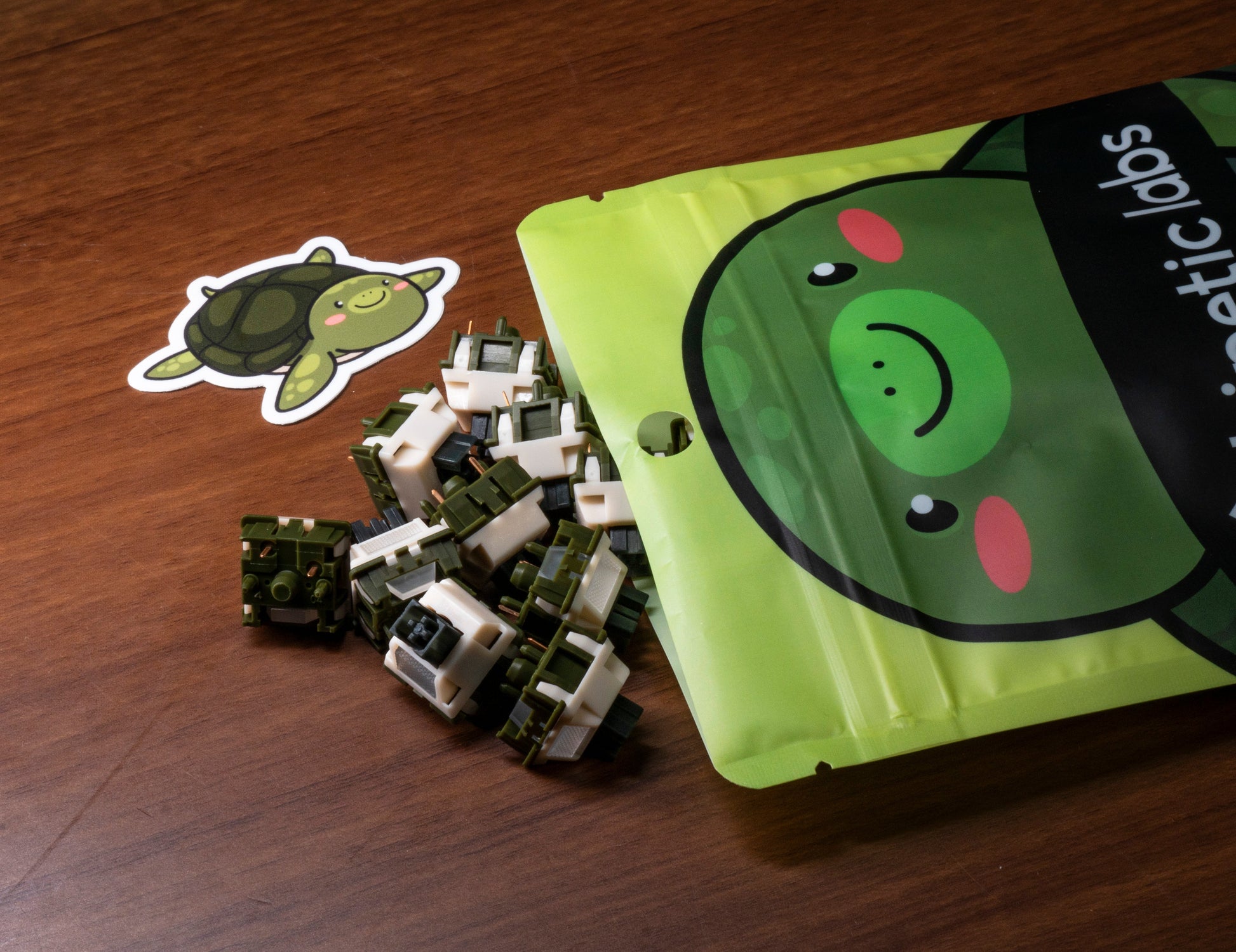 Pile of tactile keyboard switches with green and cream housings beside a green pouch