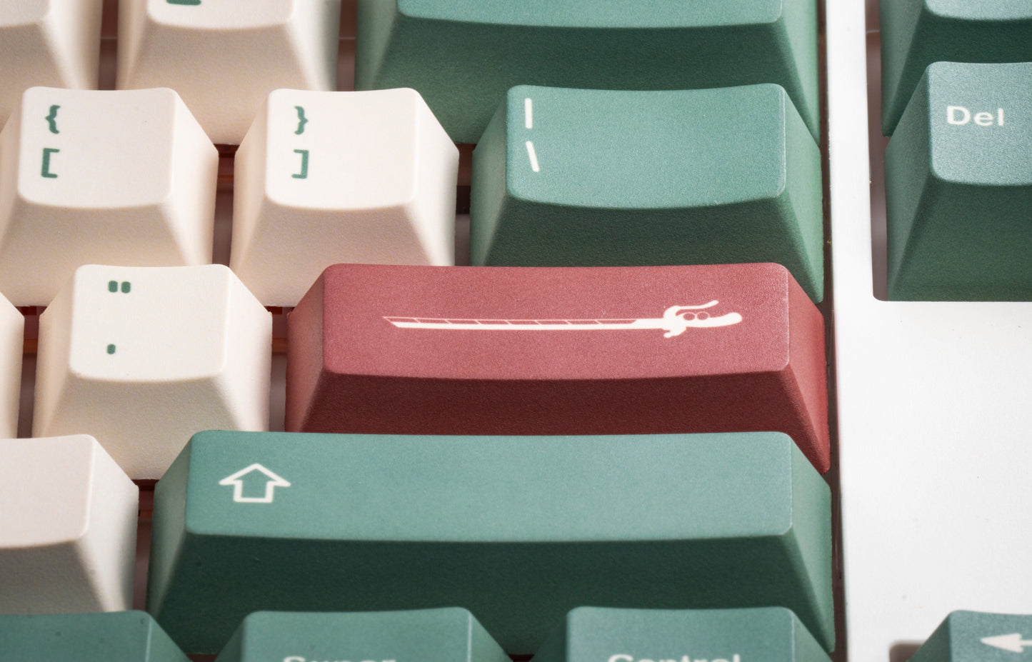 Close-up of PBT keycaps: red and green keys with white symbol legends