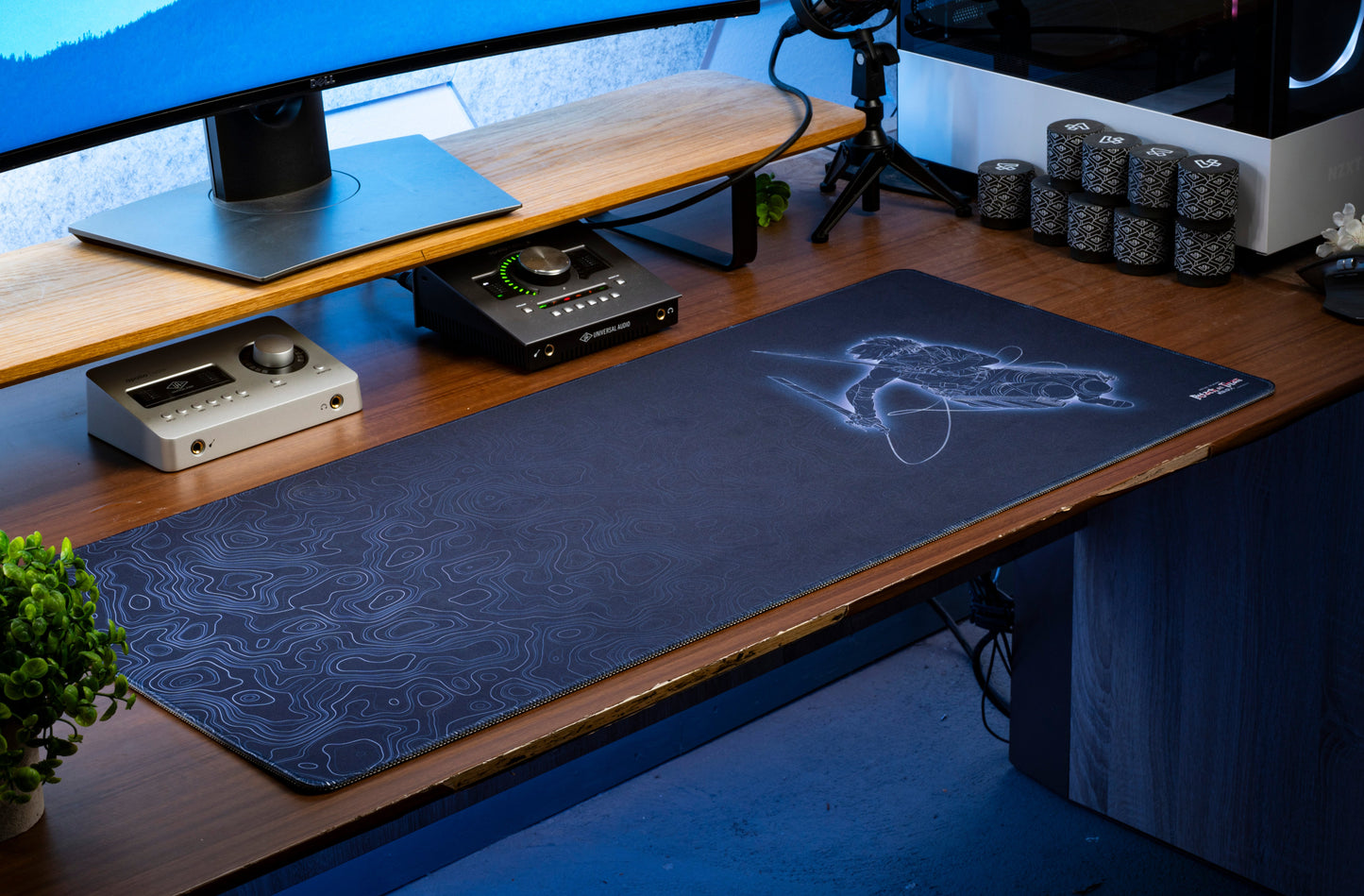 Dark blue anime desk mat with character line art and swirling topographical contour pattern