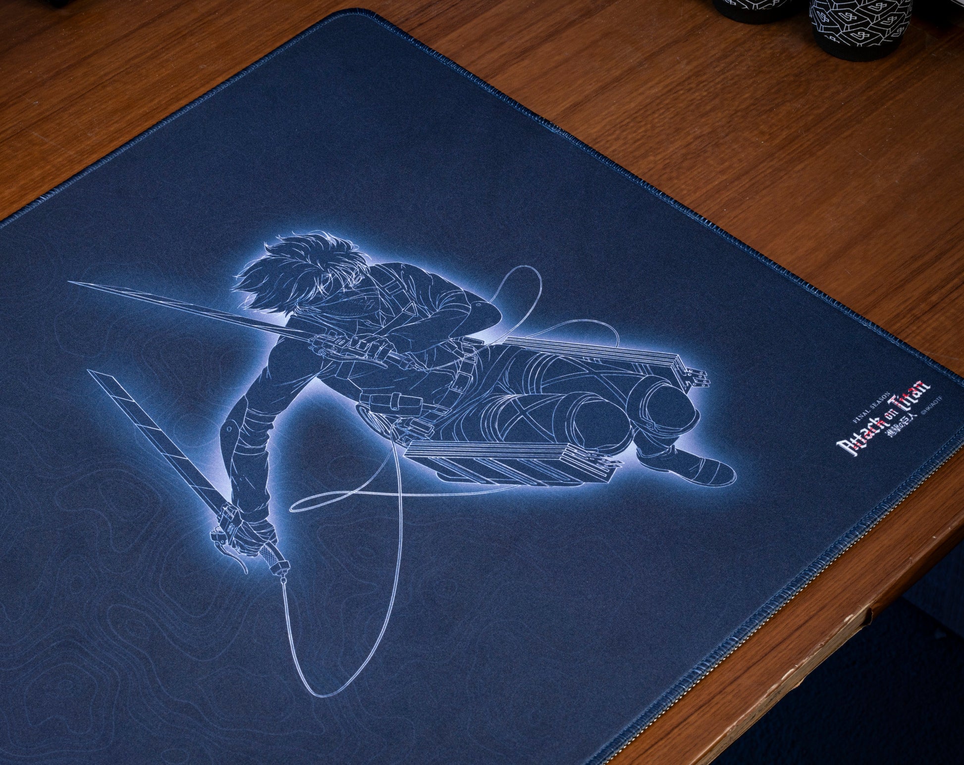Dark blue anime desk mat with character holding sword and rifle-style weapon illustration