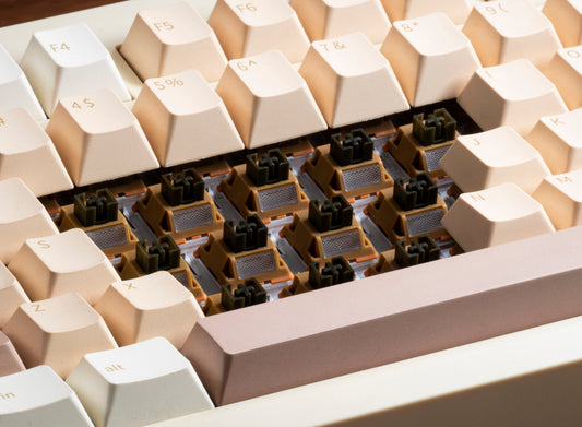 Row of linear switches with tan frames and grey contact pads in keyboard tray
