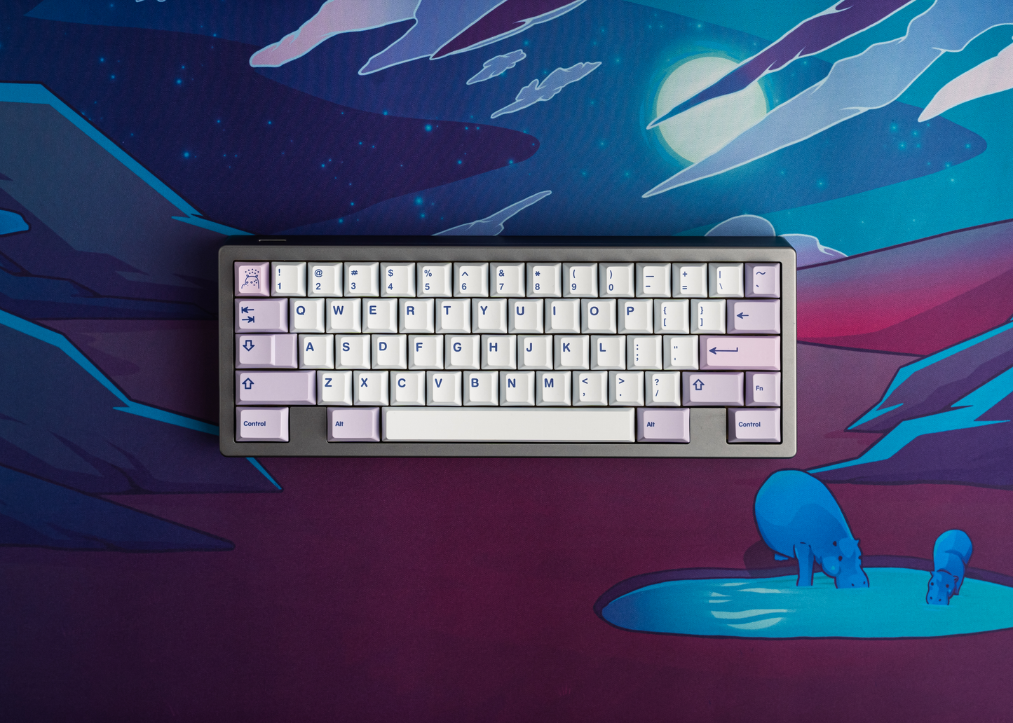 Desk mat with neon sci-fi design under keyboard, blue creatures near puddle