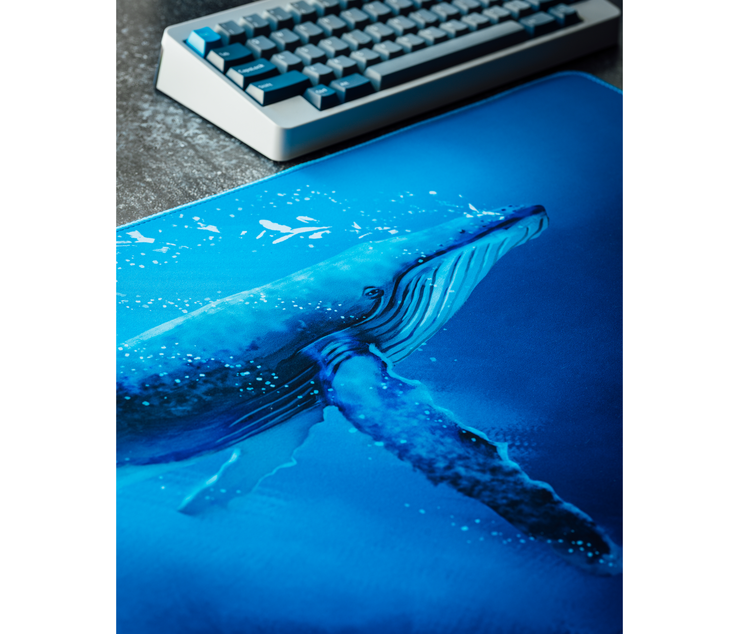 Close-up of desk mat with blue whale artwork and speckled waves