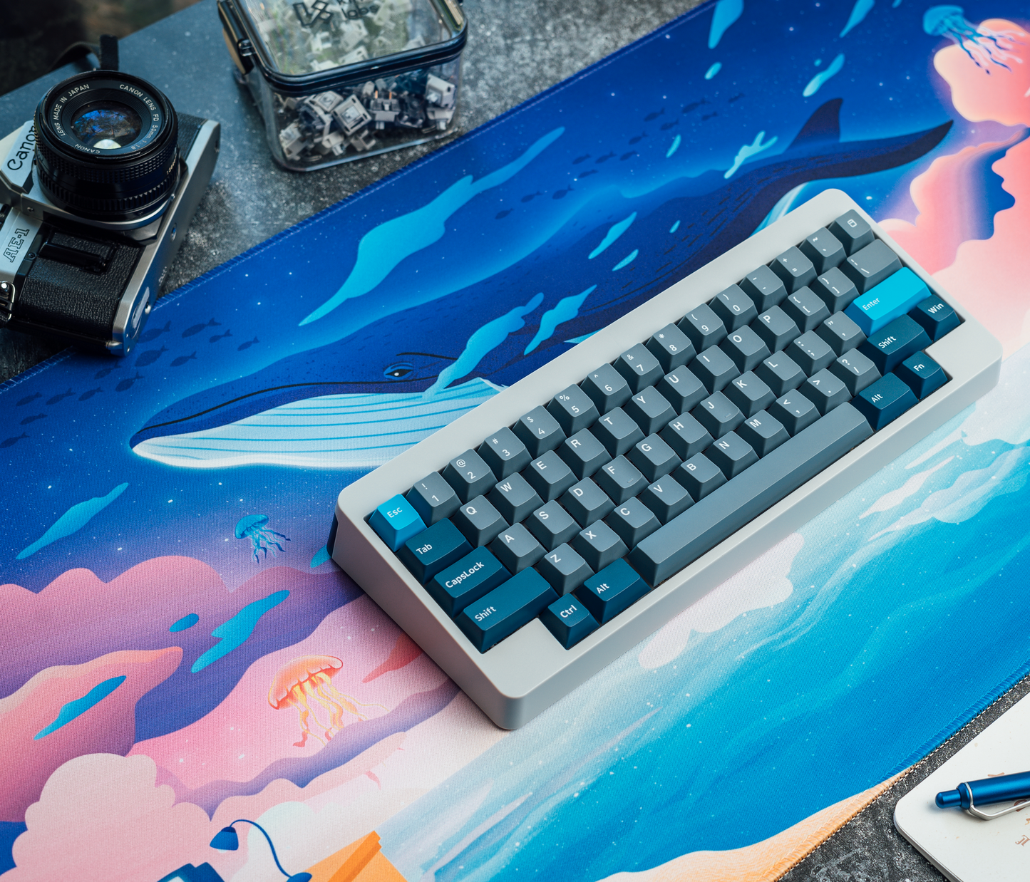Ocean desk mat under a keyboard, with whale graphic and blue, pink underwater scene