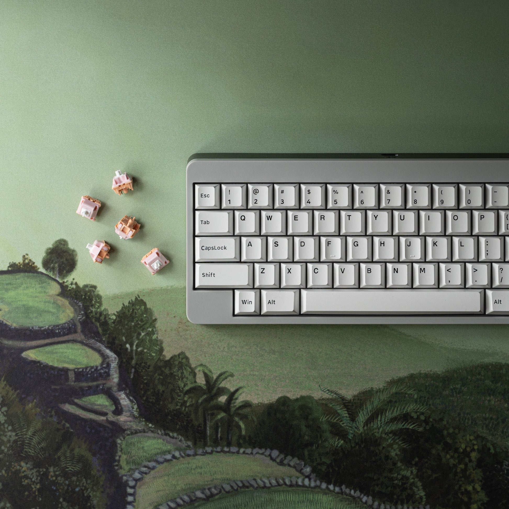 Green landscape desk mat with distant-hills print; keyboard edge visible