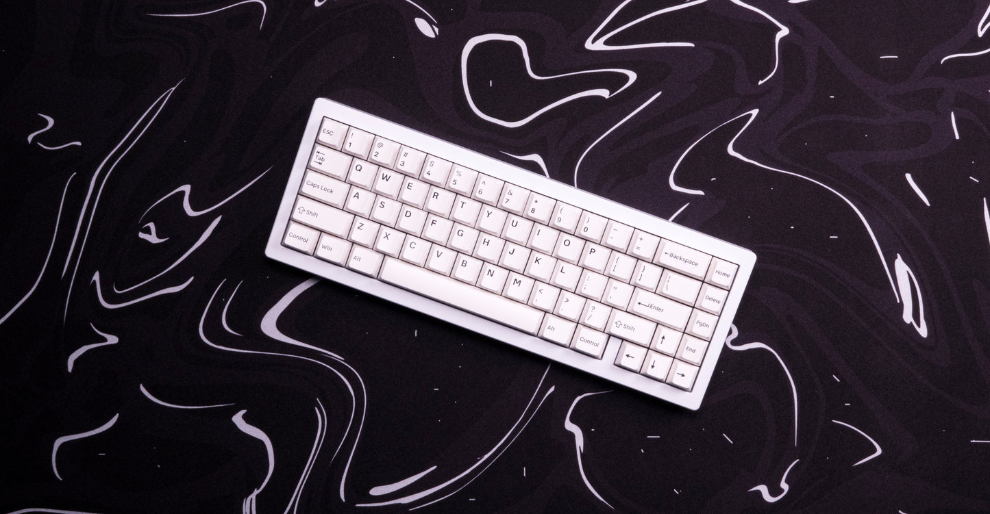 Desk mat with dark marbled liquid swirl pattern and white keyboard on top