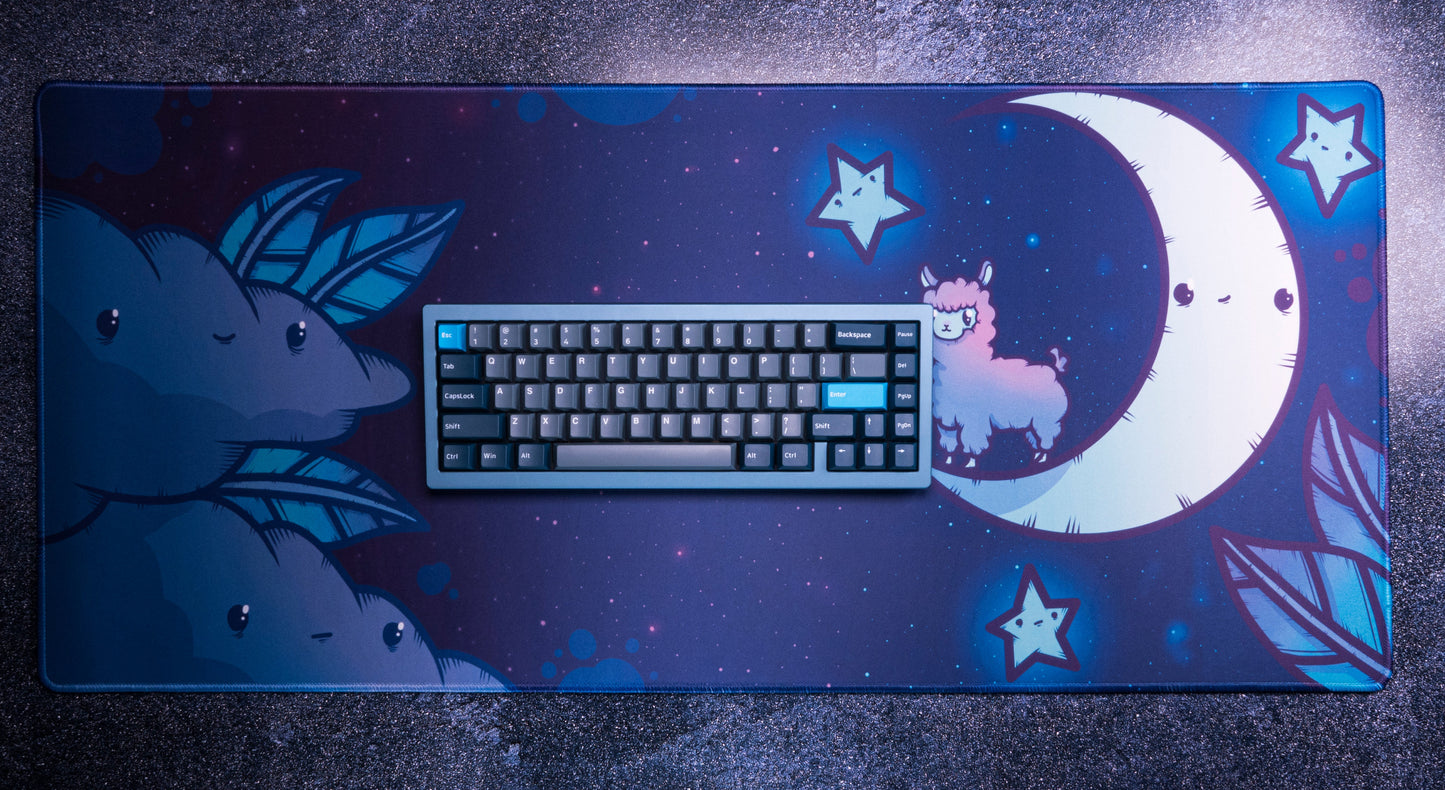 Blue desk mat with alpaca and crescent moon; keyboard resting on top