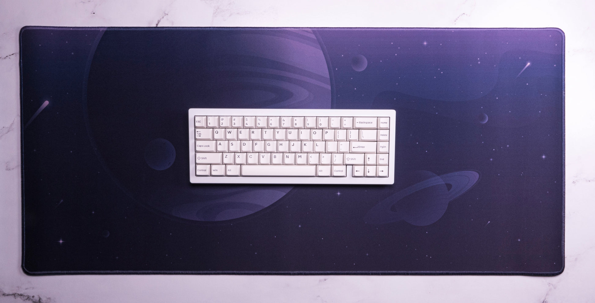 Desk mat with dark purple space print and a white keyboard centered
